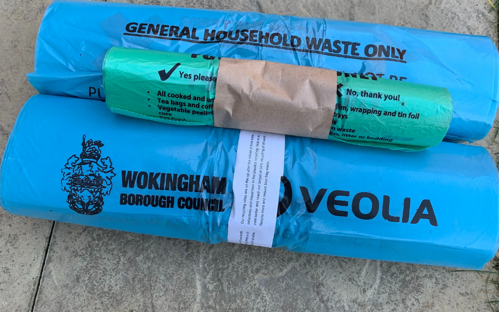 A roll of food waste bags bundled on top of two rolls of general waste bags