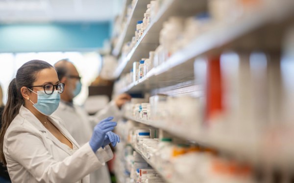 Photo shows pharmacist checking medicines on shelf