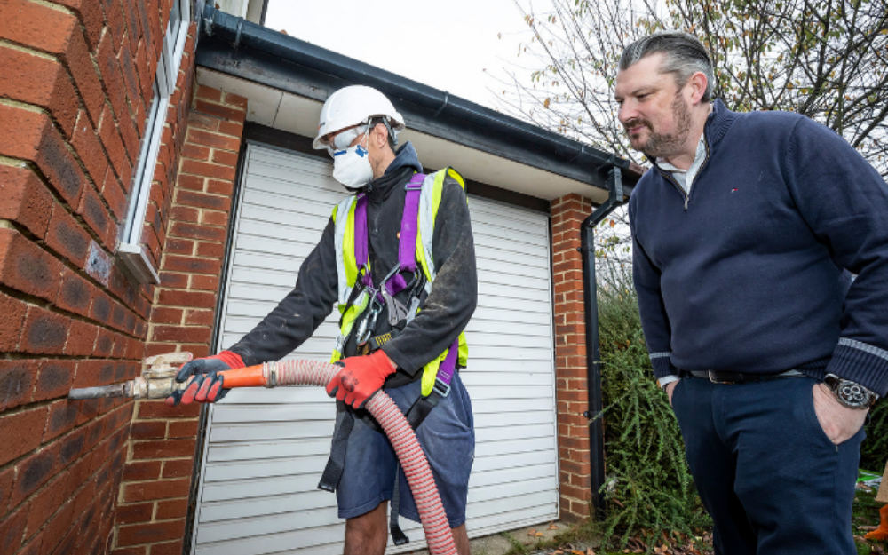 Insulation being pumped into a home paid with grant money, watched by Cllr Gregor Murray