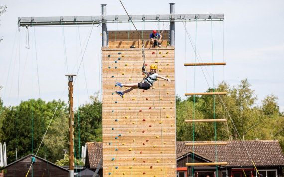 young person ziplining from outdoor climbing wall