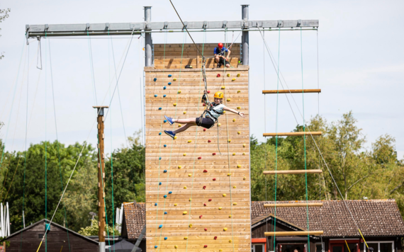 Image of a girl hanging from the climbing wall at Dinton Pastures  