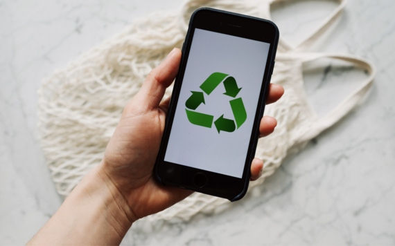image of hand holding a phone with recycling symbol displayed on the screen