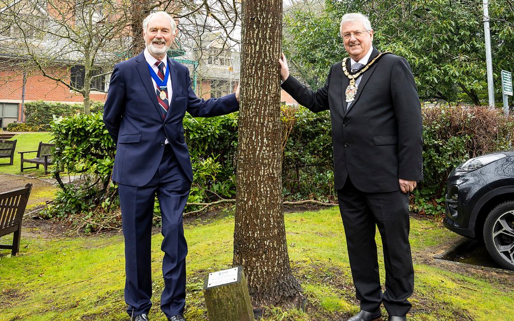 Cllr Angus Ross and Cllr Keith Baker either side of a tree, gifted to the council for its borough status