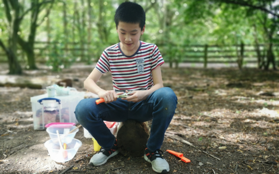 Boy sitting outside and enjoying wood crafting as part of a Wild Session 