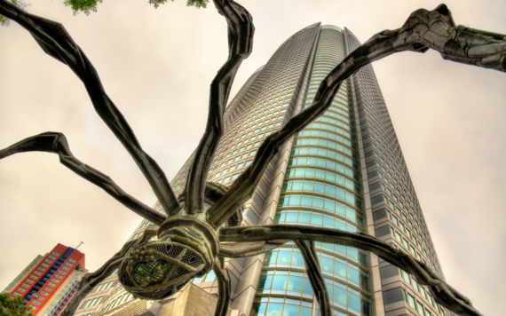 Image of a skyscraper seen through the legs of a Louise Bourgeois spider sculpture