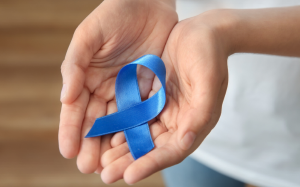 A blue ribbon, signifying bowel cancer awareness, rests on a set of hands