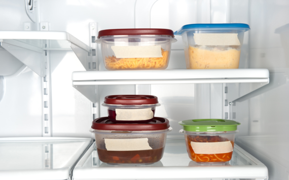 Five tupperware containers in a fridge with leftoveres inside them