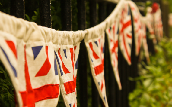 Slightly faded image of Union Jack bunting going into the distance on a garden fence 