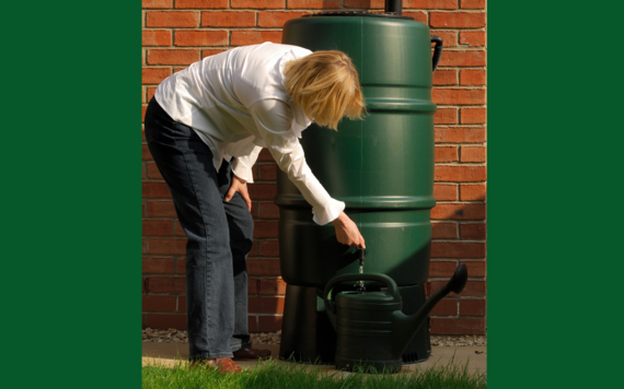 Woman bending down filling a watering can from a water butt