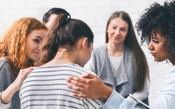 group of people consoling a woman - recovery college