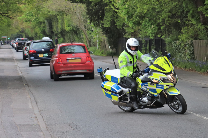 Police motorbike on road and line of cars