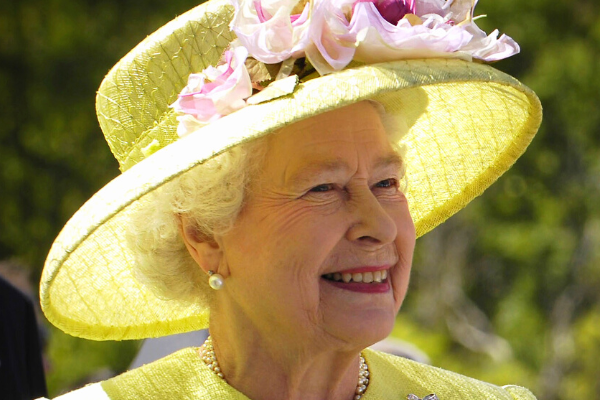 A photo of Queen Elizabeth II smiling and wearing a yellow dress and hat  