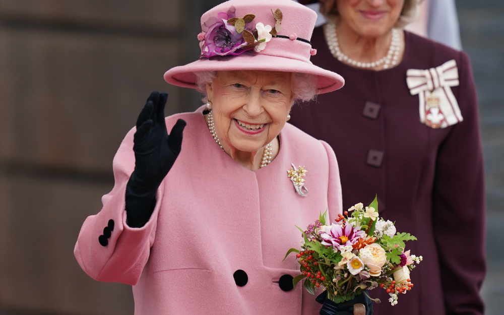 Elizabeth II, The Queen stops and waves while holding a bunch of flowers