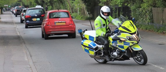 A uniformed police officer on a marked motorcycle pulling out of a junction into traffic