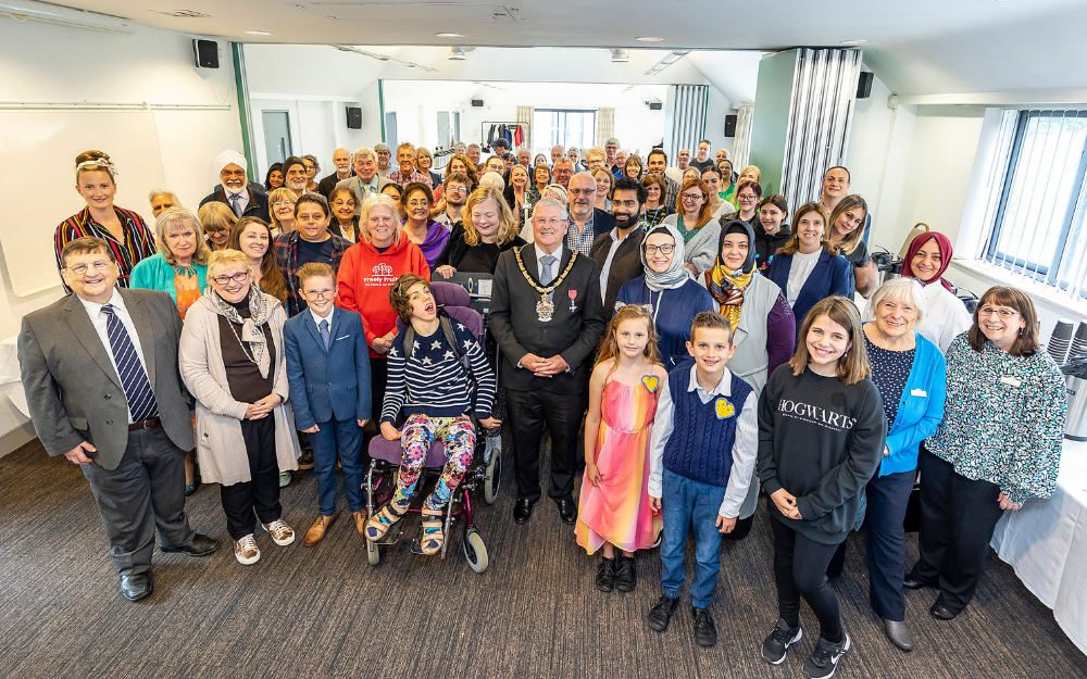 More than 100 guests crowd together to smile at the camera at the mayor's roll of honour event