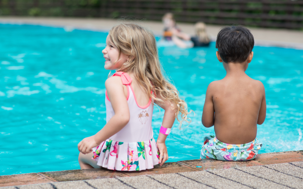 Two children sat on the edge of the California country park pool