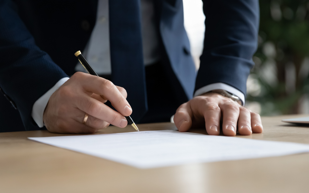 Someone standing over a letter signing it