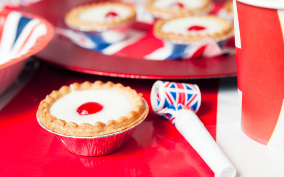 Image of a plate of individual cakes on a union jack print plate and themed party wear. 