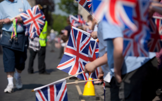 Image of people waving hand held Union Jack flags at a community event