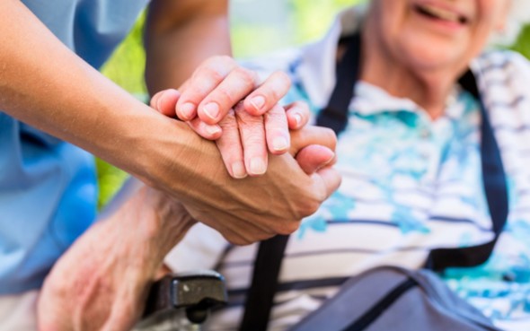 Photo of an older pair of hands being held by a carer