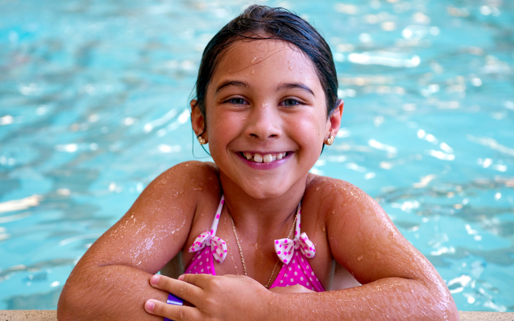 A child in a swimming pool smiles to the camera