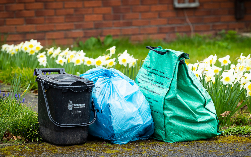 A food waste caddy, blue rubbish bag and green recycling bag at the kerbside