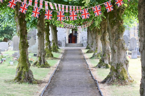 A line of trees with union flag bunting leading to entrance of a church