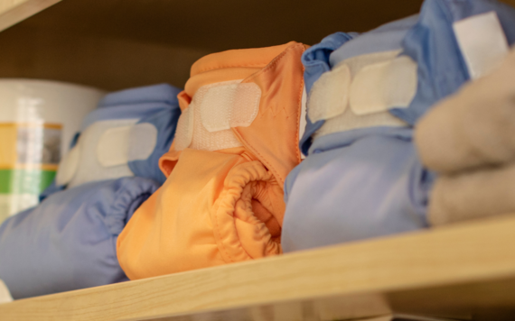 Four real nappies in blue, orange and beige colour in a cupboard