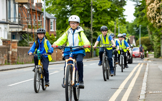 Six students from Piggott school cycling along road in a line wearing reflective jackets