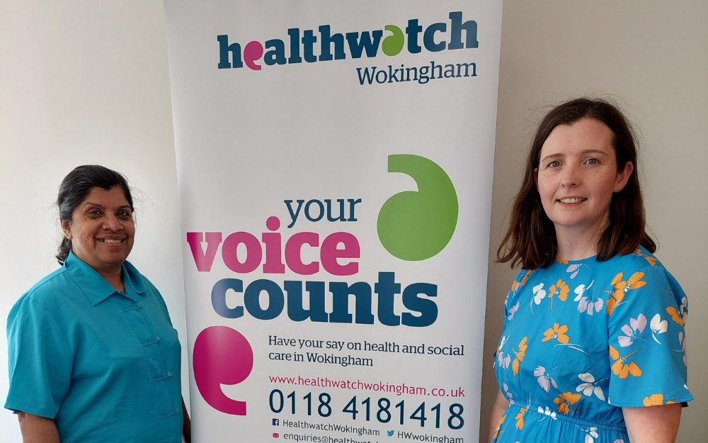 Alice Kunjappy-Clifton (l) and Grainne Colgan of Healthwatch Wokingham Borough smile to the camera either side of their branded banner