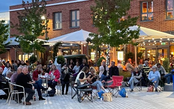 People sitting outdoors listening to music in the evening at Peach Place