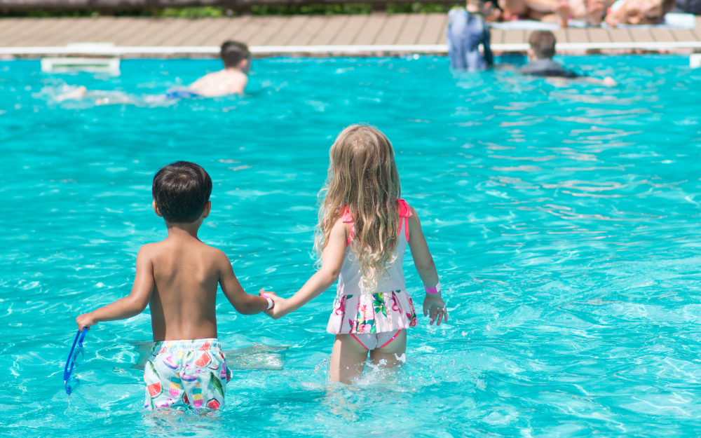 A girl and boy hold hands while standing in the California Country Park paddling pool