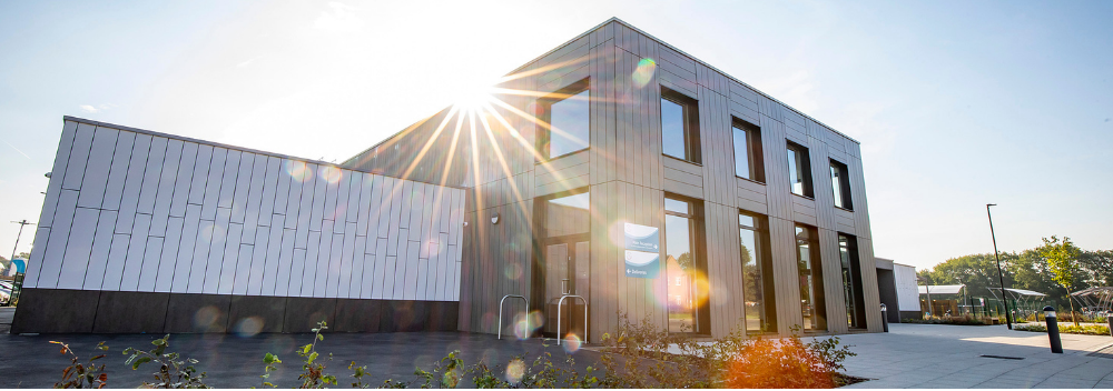 cropped wide image of Farley Hill Primary School, with the sun rising above the building line.