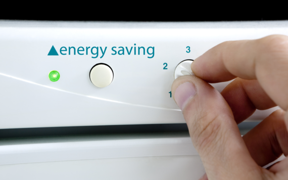 A hand turning on a home appliance with the words energy saving on it