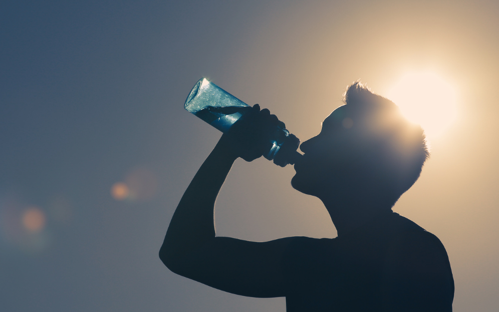 Man drinking from a water bottle on a sunny day