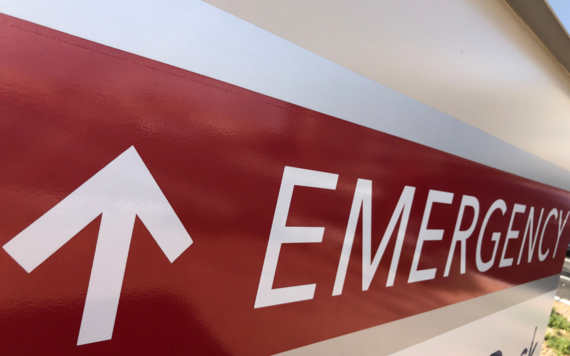 A red sign with the word emergency and an upward arrow in white