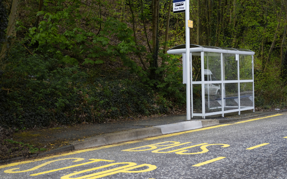 A bus stop with road markings and a shelter