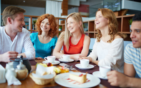 A photos of three young women and two men having tea together 