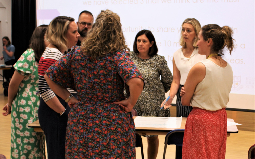 Teachers stand in a cluster discussing what they can do to tackle climate change