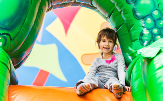 A child sitting on the top of an inflatable slide