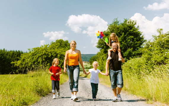 A family of five walking on a footpath in a meadow