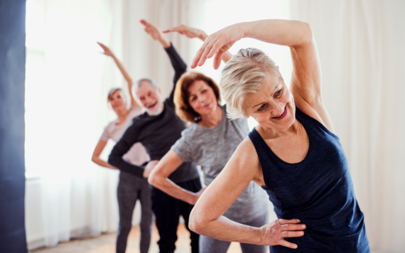 A group of older people taking part in a stretch class