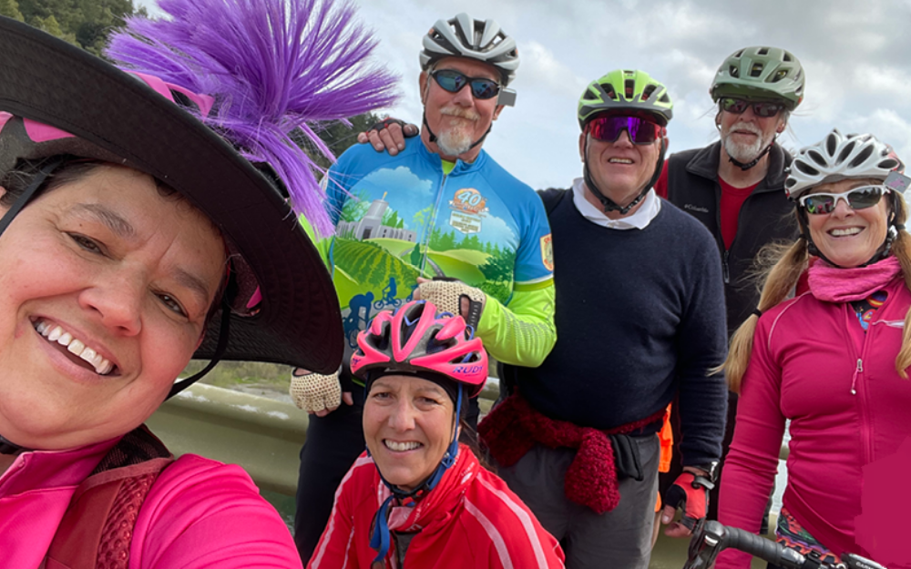 Groups of cyclists in helmets smile into the camera