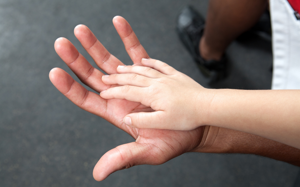 A child's hand resting on an adult's hand