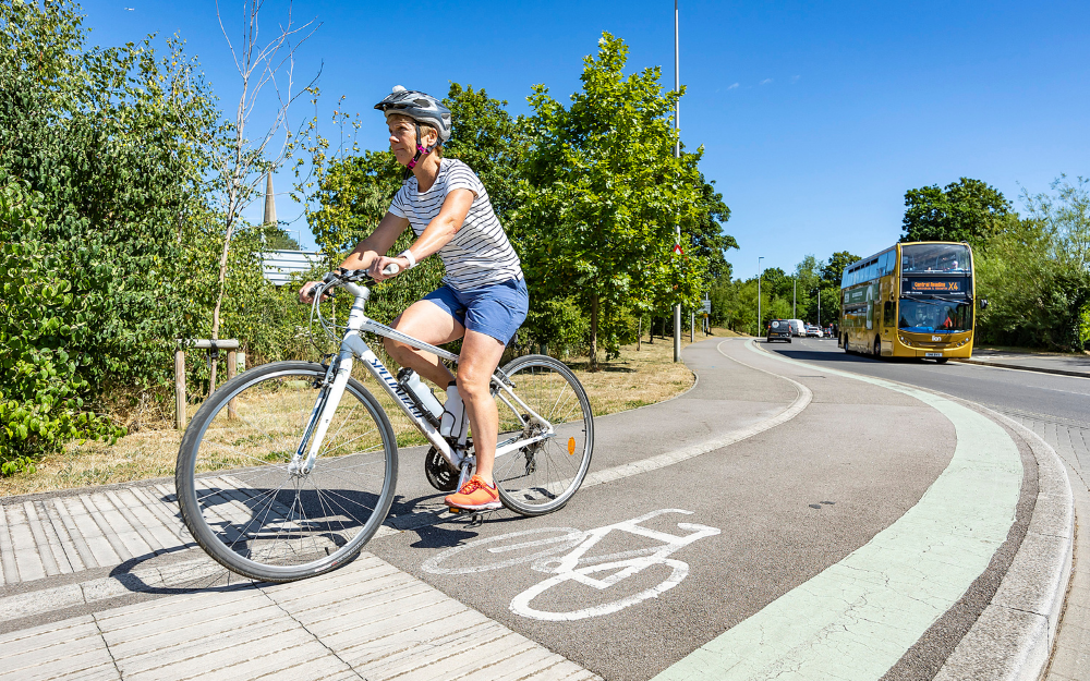 A women cycles on a dedicated cycle path, next to a road in Wokingham borough