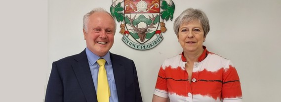 council leader Clive Jones and Maidenhead MP Theresa May smiling in front of the borough council's crest