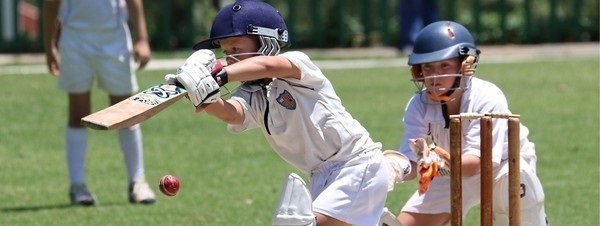 shot of a child playing cricket and batting with another keeping the wicket behind him