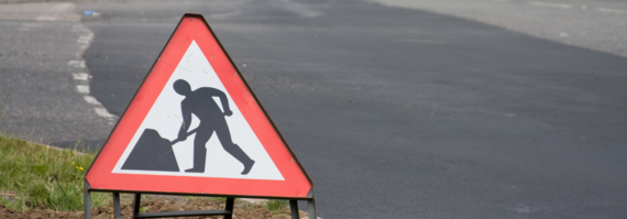 a triangular road works sign by the roadside