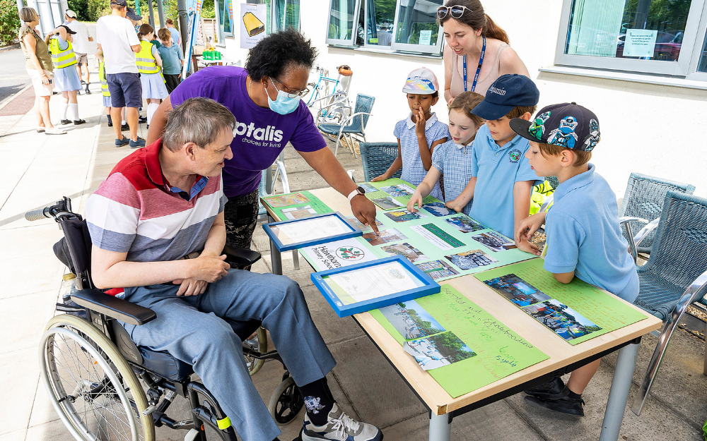 A man in a wheelchair and his carer take a look at a stand run by schoolchildren at Waste Action Day