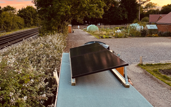 A solar panel on top of a tool shed in an allotment 